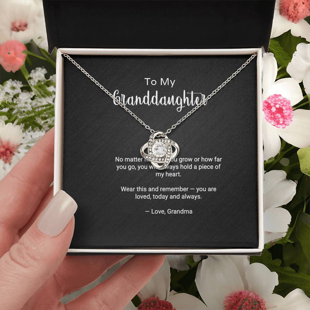 To My Granddaughter Love Knot necklace with 'Always in My Heart' message card, held in hand in gift box